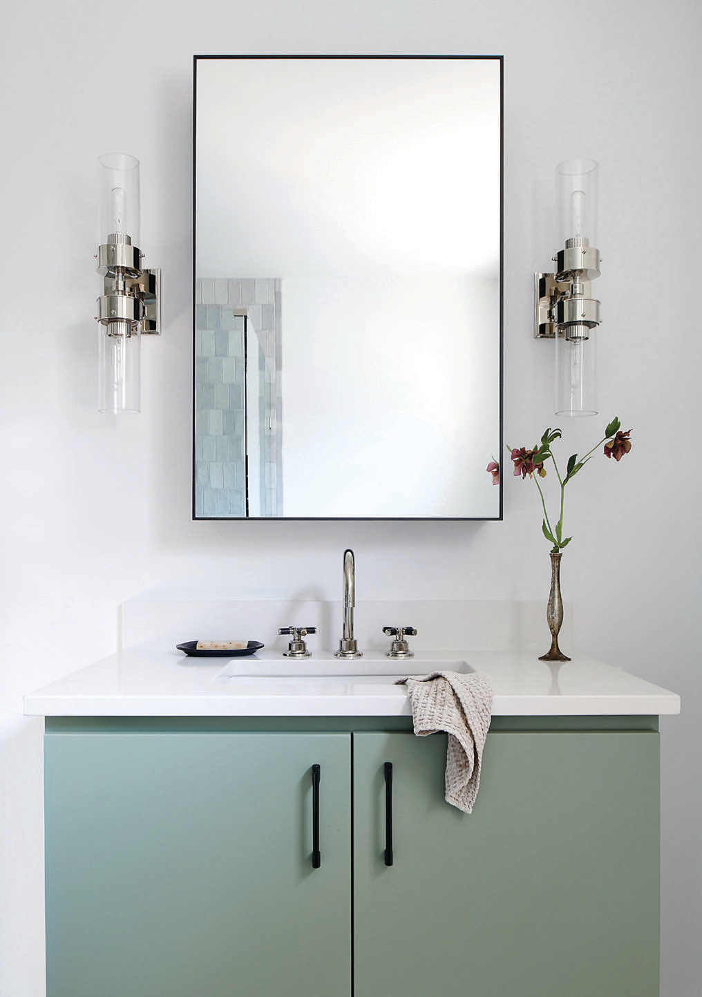 The guest bathroom’s sage-hued midcentury-styled vanity adds a wash of subtle color. The couple’s son, who often visits, weighed in on the design of this bathroom.